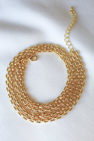 The Basque Necklace by Kinsey Designs Archives features a chunky chain and adjustable clasp, displayed coiled in a circle on a white fabric background.