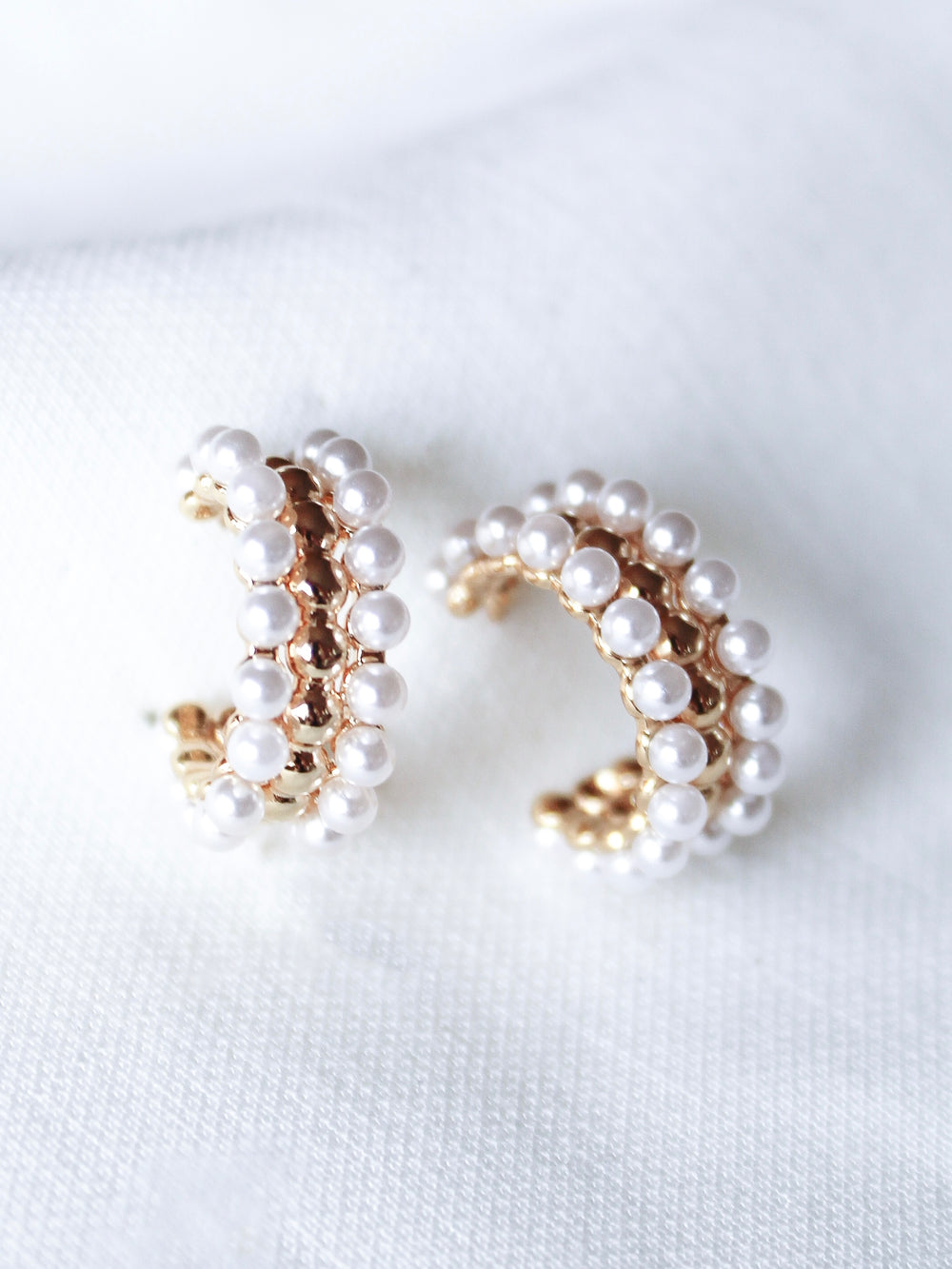 Elsie Hoop by Kinsey Designs Archives: gold hoop earrings with small white pearls, elegantly shown on a white textured fabric.