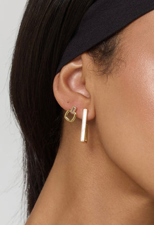 Close-up of a woman’s ear wearing Kinsey Designs Lucky Post geometric gold filled earrings—one rectangular and one square, each about 0.5" long—paired with a black headband.