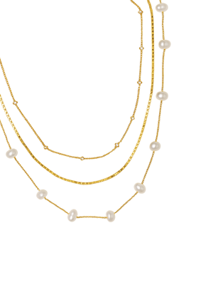 The Folly Layer Necklace by Kinsey Designs Archives features three layers—two pearl necklaces and one gold chain with delicate beads—elegantly displayed on a white background.