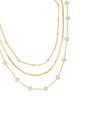 The Folly Layer Necklace by Kinsey Designs Archives features three layers—two pearl necklaces and one gold chain with delicate beads—elegantly displayed on a white background.
