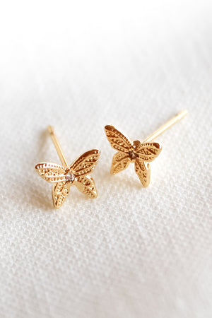 Flutter Stud earrings by Kinsey Designs Archives feature gold-filled, butterfly shapes with delicate details, shown on a soft white fabric background.