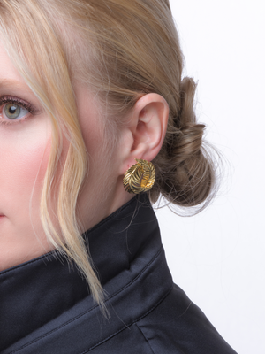 Close-up of a woman with blonde hair in a bun, wearing Kinsey Designs' Georgie Twisted Leaf Earrings and a dark collared top.