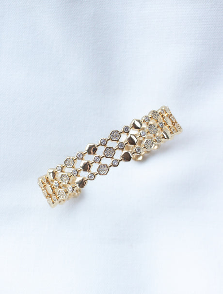 The Honey Cuff by Kinsey Designs Archives features hexagonal and circular gold-filled links, some adorned with small stones. This adjustable bracelet adds subtle elegance—discover it at our sample sale, displayed on white fabric.