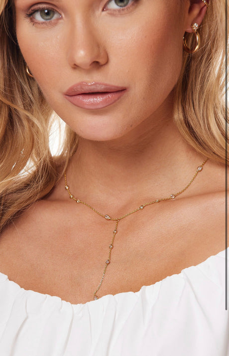 Woman wearing the Hugo necklace by Kinsey Designs Archives, paired with 1-inch wide hoop earrings and an off-the-shoulder white top.