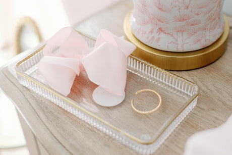 The Fallon Mama & Baby Cuff Set by Kinsey Designs is displayed on a clear tray atop a wooden surface near a decorative container.