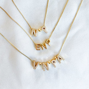 Three gold filled Nurse Charm Necklaces by Kinsey Designs rest on white fabric—perfect as a meaningful profession necklace or unique gift.