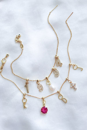 Three gold necklaces with Kinsey Designs Archives Letter Grip Charms and jeweled accents displayed on white fabric—ideal for personalized jewelry lovers seeking a unique, gold-filled charm.