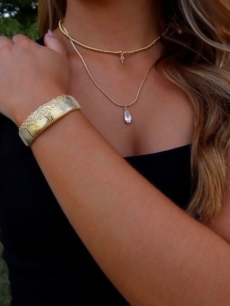 A woman wearing the Kinsey Designs Charlotte Drop Necklace, featuring a teardrop cubic zirconia pendant, paired with a matching bracelet.