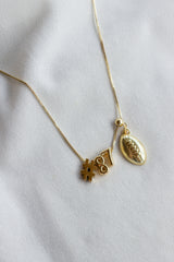 Gold filled necklace with pendant charms: hashtag #, number 87, and a Football Drop Charm - Kinsey Charm Bar on a white fabric background.