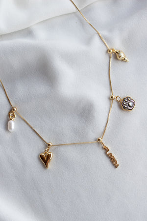 The Kinsey Designs Pearl Paw Grip Charm features a gold necklace with heart, paw print, LOVE pendant, mother-of-pearl, and hand charms—perfect pet lover jewelry for any occasion.