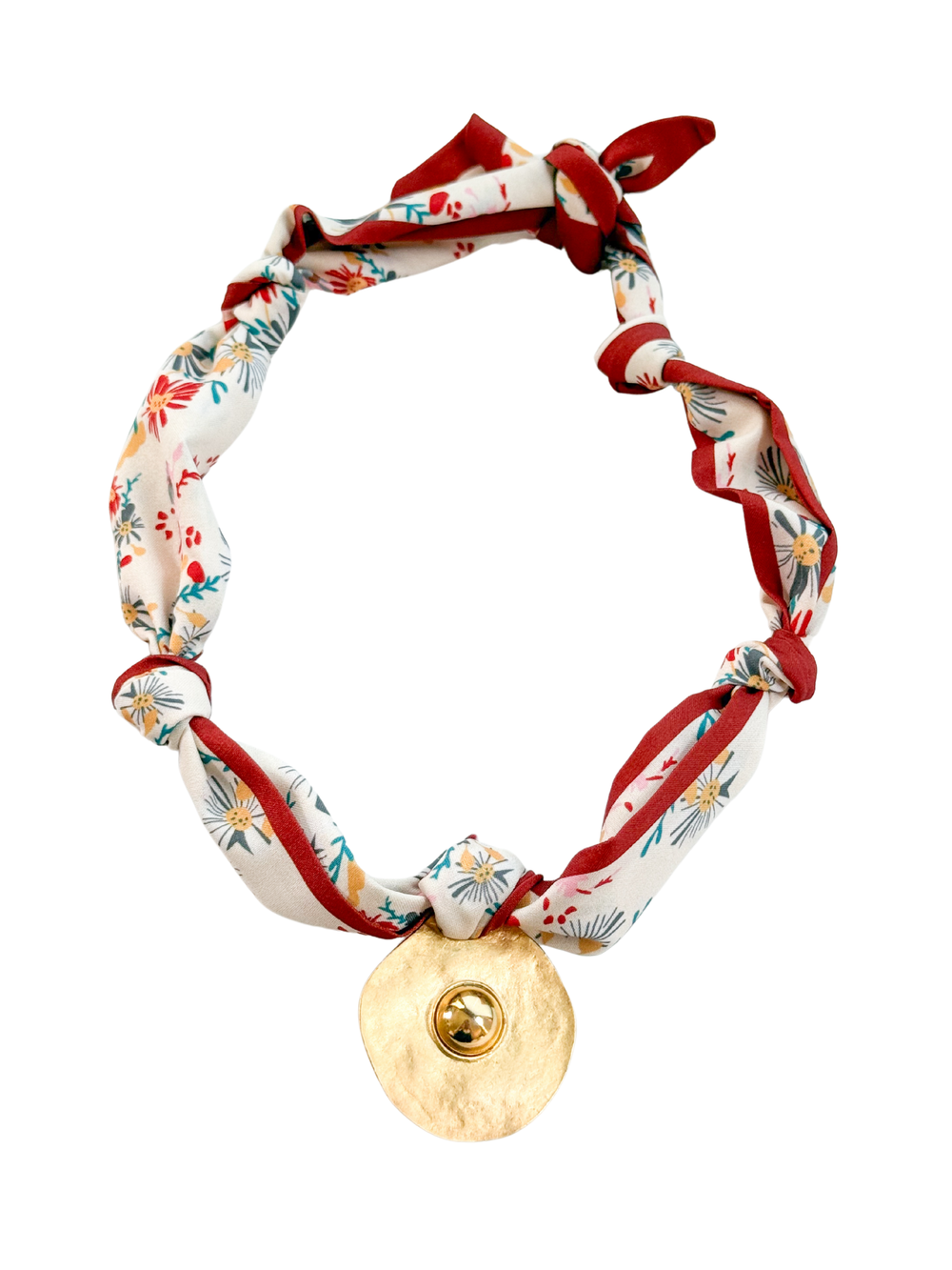 The Imperia Scarf Necklace by Kinsey Designs features a floral-patterned fabric and a gold-toned, irregular round pendant, doubling as an adjustable scarf necklace for versatile styling.
