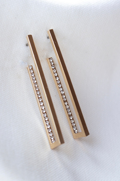 The Inside Job Hoop by Kinsey Designs Archives features gold-filled rectangular earrings adorned with a row of sparkling cubic zirconia, elegantly displayed on white fabric. Ideal for those seeking sample sale prices on stylish earrings.