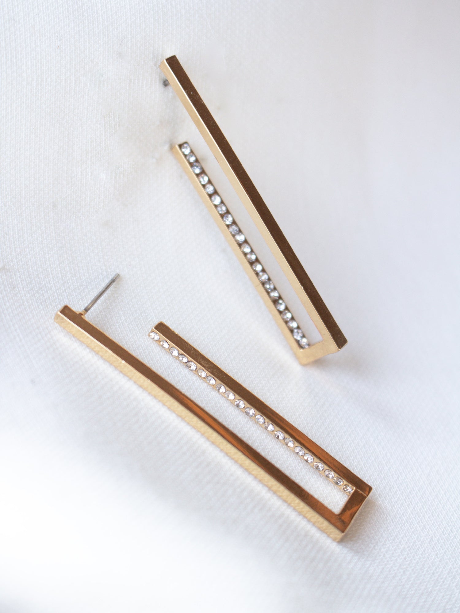 The Inside Job Hoop by Kinsey Designs Archives: rectangular gold-filled earrings with a row of cubic zirconia, showcased on white fabric. Enjoy elegant style at an exclusive sample sale price.