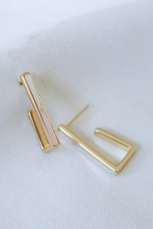 The Kai Earring by Kinsey Designs Archives features gold filled, minimalist rectangular and L-shaped designs, each 1 inch long, displayed on a white fabric background.