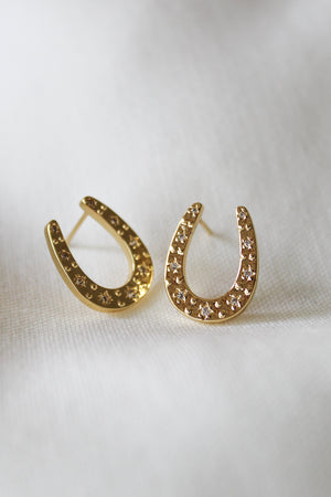 The Kent Earring by Kinsey Designs features gold-filled, horseshoe-shaped hoops with small sparkling stones, shown on a white fabric background. Limited availability—final sale.