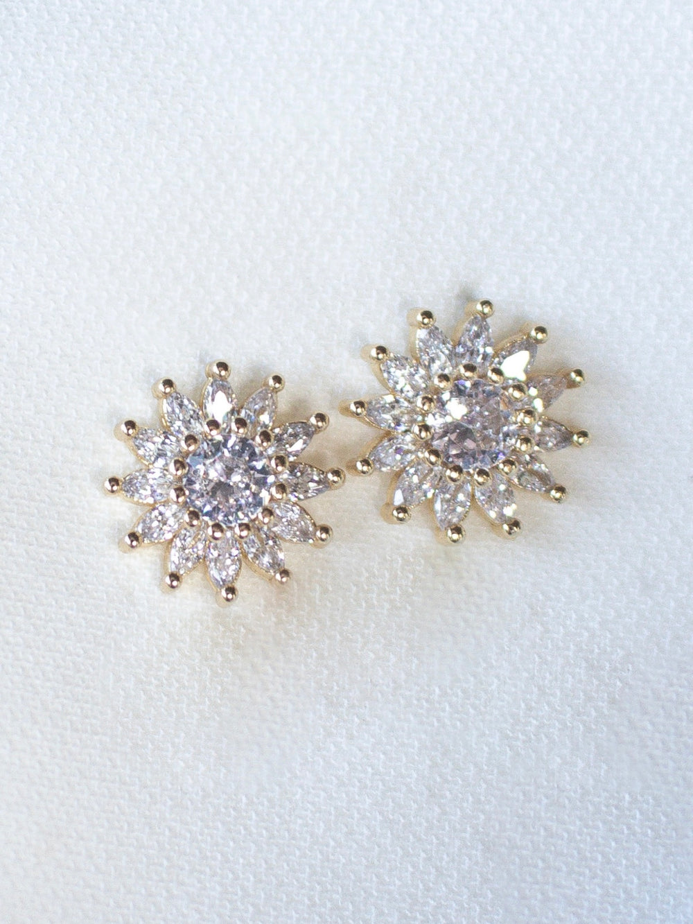 The Lana Stud by Kinsey Designs Archives features gold filled floral studs with sparkling CZ accents, displayed on a soft white fabric background.
