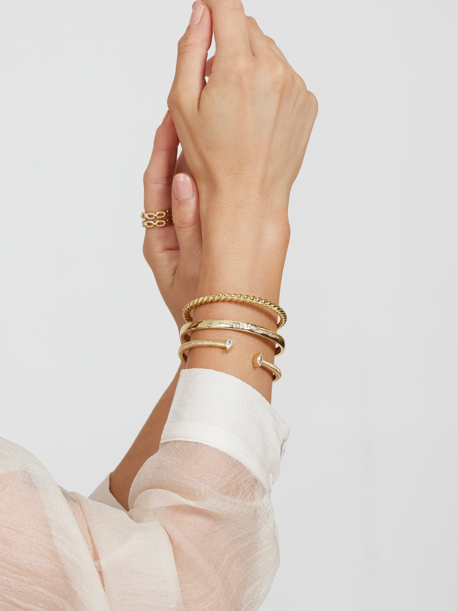 A hand wearing the Kinsey Designs Archives Lily Cuff bracelet and a ring, shot against a white background with a sheer white sleeve visible.