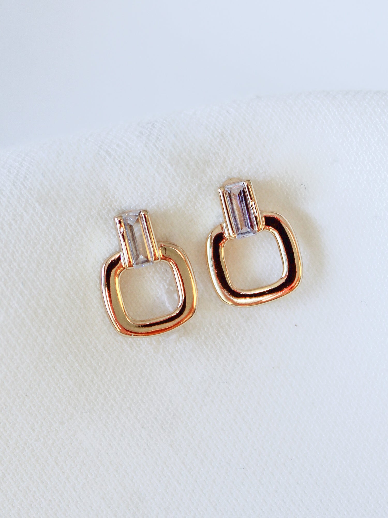 Kinsey Designs Lucky Post earrings feature gold-filled and crystal studs in geometric shapes, each measuring 0.5" long, shown on a white fabric background.