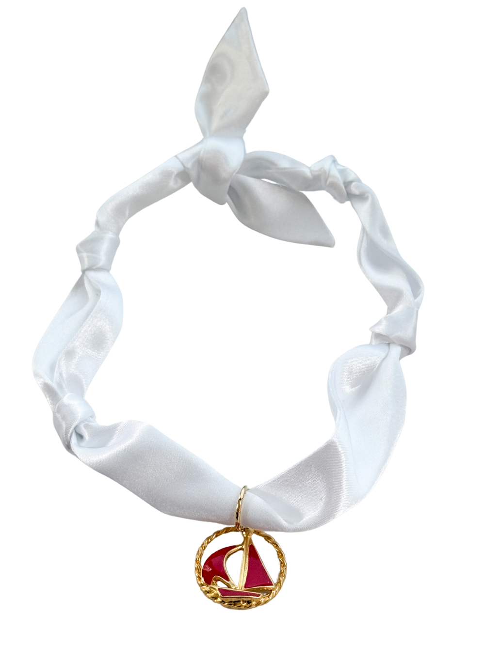 The Modena Scarf Necklace by Kinsey Designs features a white satin scarf with a knot and a gold and red sailboat vintage pendant, offering versatile style as an adjustable, one-of-a-kind scarf necklace.