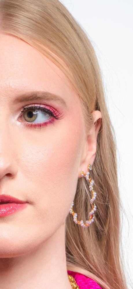 Close-up of a woman's face with pink makeup wearing the Kinsey Designs Archives Mac Hoop, a large 2" gold filled beaded earring, against a white background.