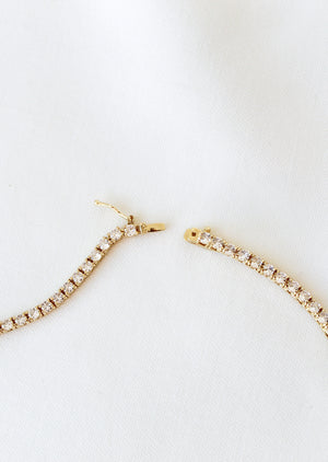 The Malia Tennis Necklace by Kinsey Designs Archives, shown unclasped on white fabric, pairs perfectly with a bracelet and is available now at our sample sale.