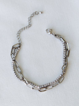 The Marc Tennis Bracelet by Kinsey Designs, featuring sparkling rhinestones and rhodium plating, is displayed on a white fabric background.