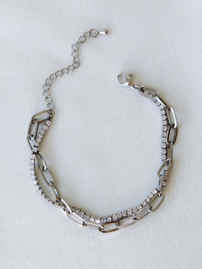 The Marc Tennis Bracelet by Kinsey Designs, featuring sparkling rhinestones and rhodium plating, is displayed on a white fabric background.