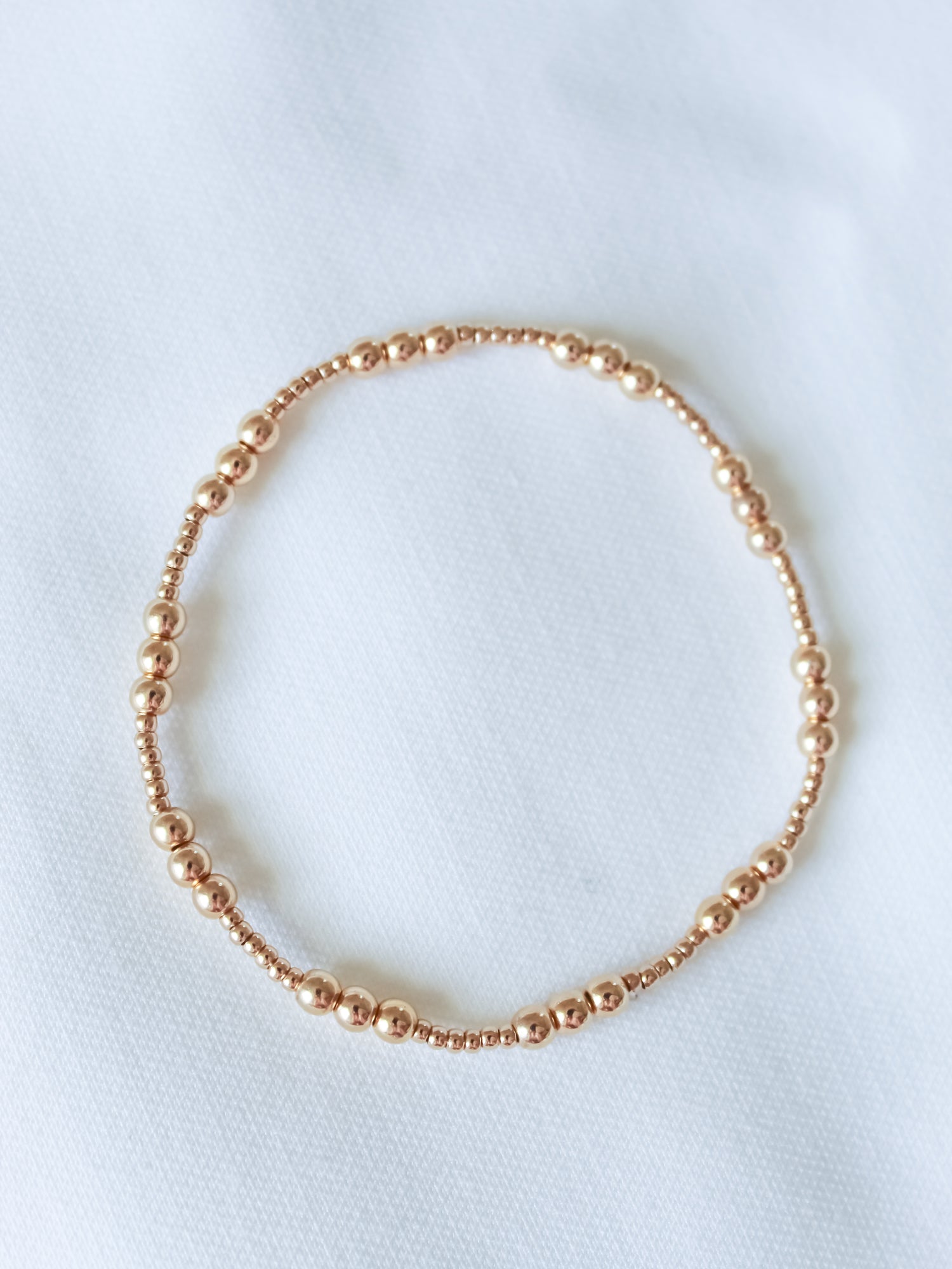 The Mia Bracelet by Kinsey Designs features a delicate gold-filled beaded, adjustable stretch design and is shown on a white fabric background. Available in multiple sizes—an ideal sample sale find.