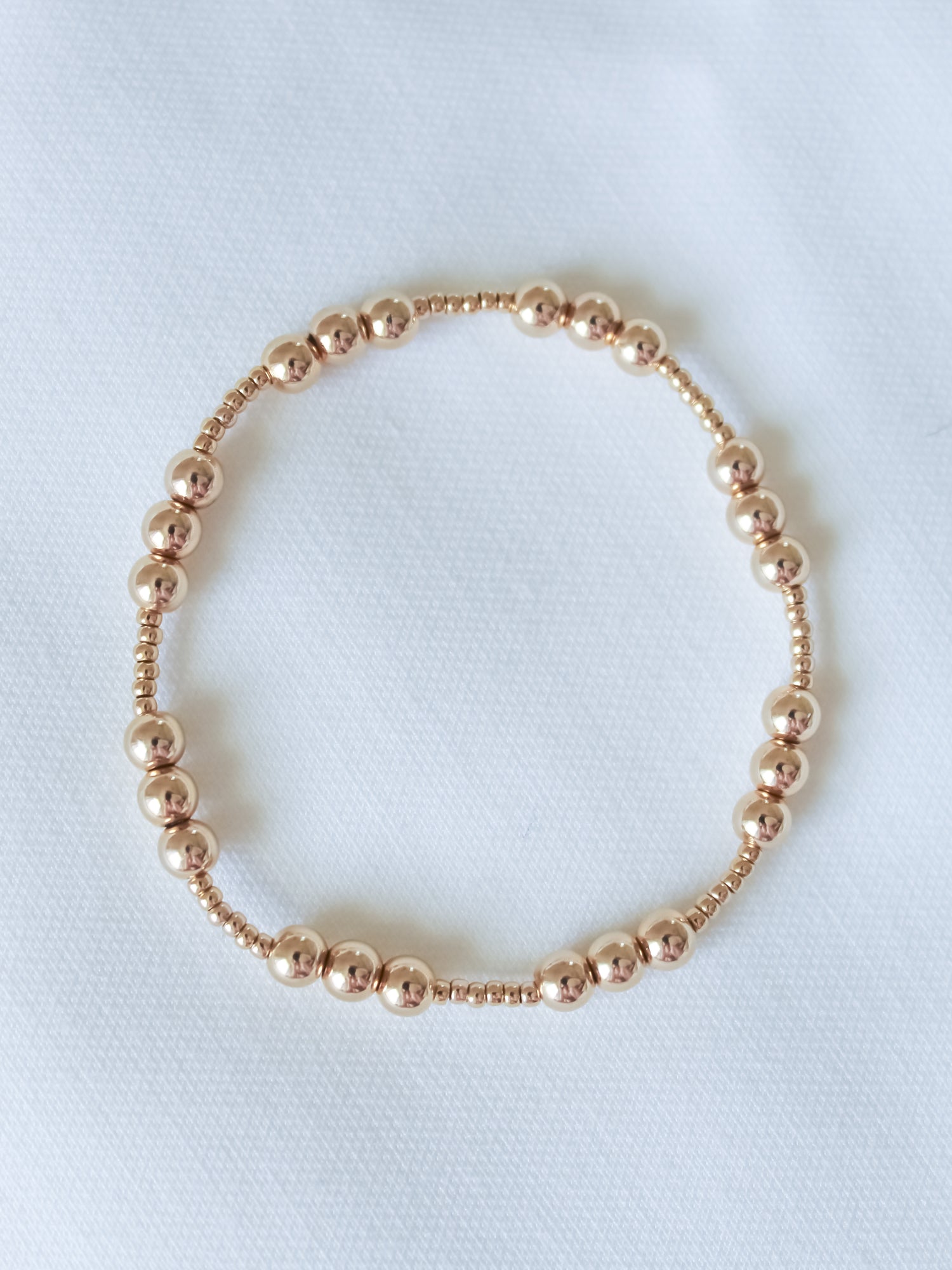 The Mia Bracelet by Kinsey Designs, shown in a circular arrangement on white fabric, features an adjustable stretch design and comes in multiple sizes—ideal for finding your perfect fit at a sample sale.