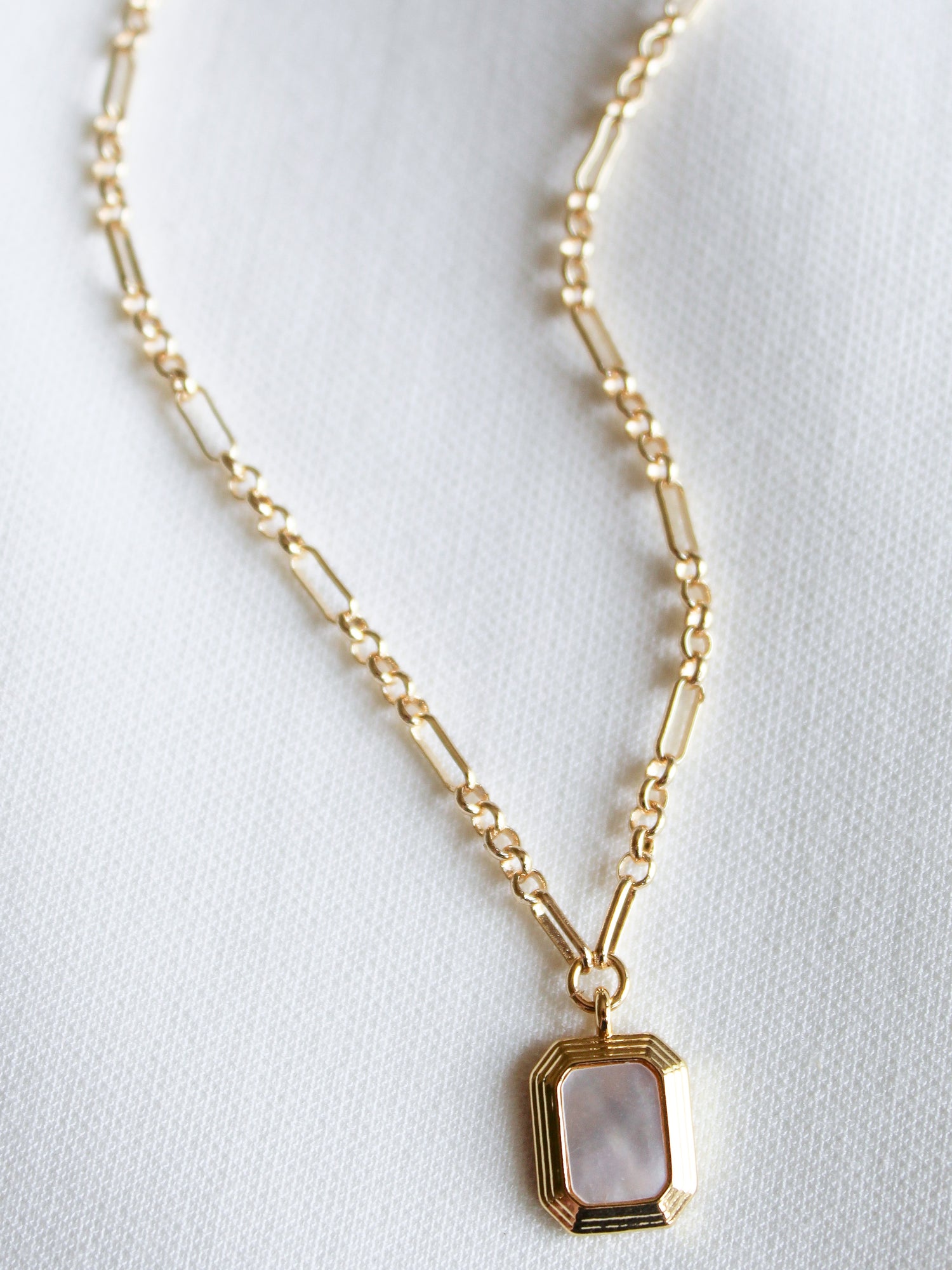 The Mirabelle Pendant Necklace by Kinsey Designs Archives features a gold-filled 20" chain with a rectangular mother-of-pearl pendant, showcased on white fabric—a perfect pick from our sample sale.