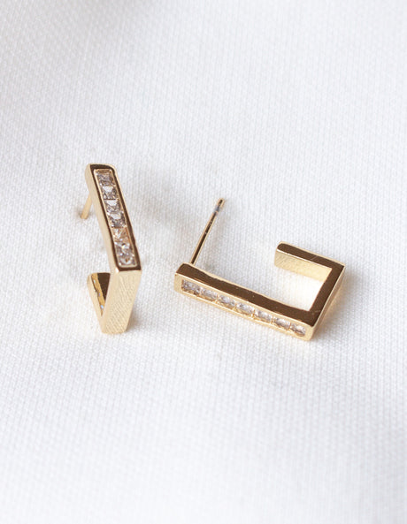 The Oak Hoop by Kinsey Designs Archives: gold-filled geometric earrings with small embedded crystals, showcased on a white textured fabric. Elevate your style—shop them now at our exclusive sample sale!.