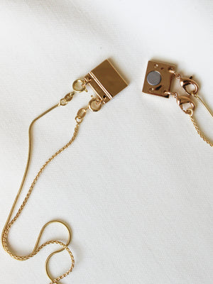 The Orion Detachable Necklace by Kinsey Designs features a gold filled chain with a magnetic clasp, elegantly displayed on a white textured surface for stylish convenience.