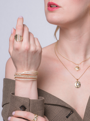 Woman wearing the Kinsey Designs Petra Ring, featuring a bold statement style, along with bracelets and layered necklaces, paired with red lipstick and an off-shoulder blazer.