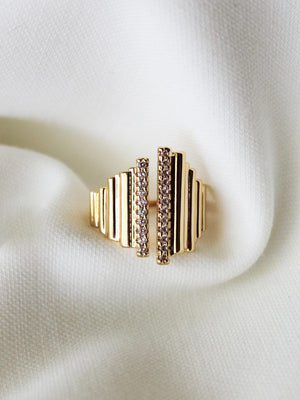 The Kinsey Designs Petra Ring features a vertical bar design with small gemstones, shown on white textured fabric—a stunning statement piece for any occasion.