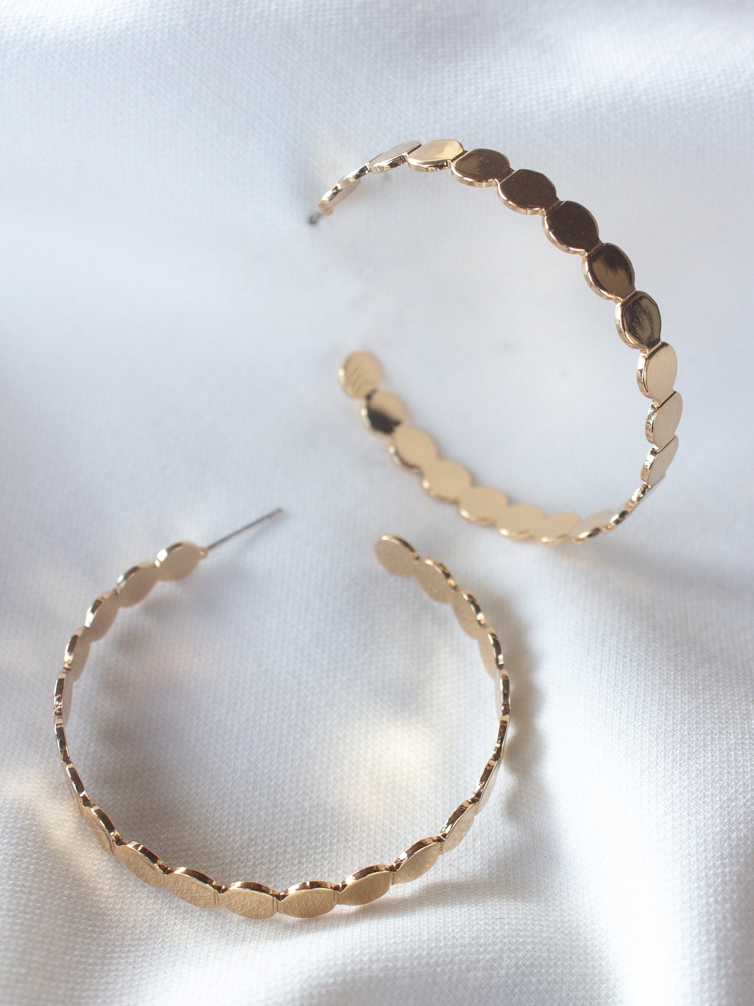 The Round and Round Hoop earrings by Kinsey Designs Archives feature a scalloped gold-filled design, 2" wide, shown on white satin fabric.
