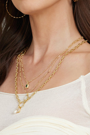 A woman wearing the Kinsey Designs Archives Sophie Pearl Necklace and hoop earrings, dressed in a white top.