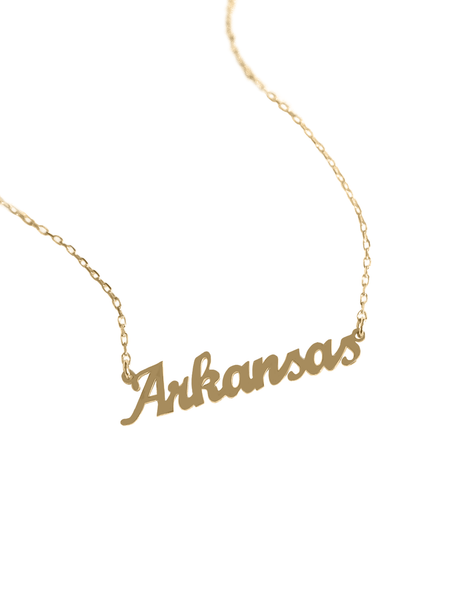 The Kinsey Designs Archives State of Mind Necklace features a gold filled “Arkansas” pendant in cursive on a white background.