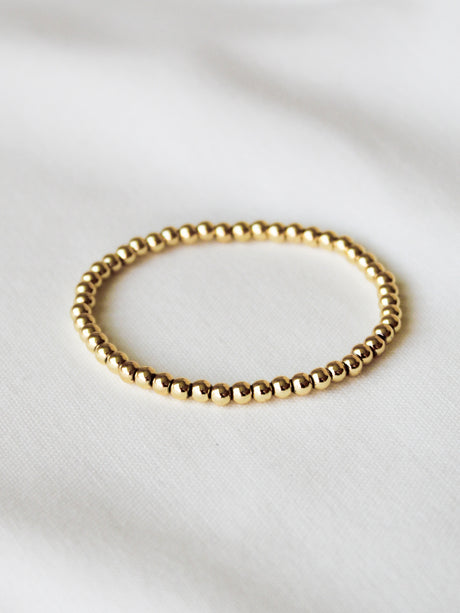 The Kinsey Designs Stretch Bead Bracelet 4MM rests on a white fabric background, perfect for stacking with your favorite styles.