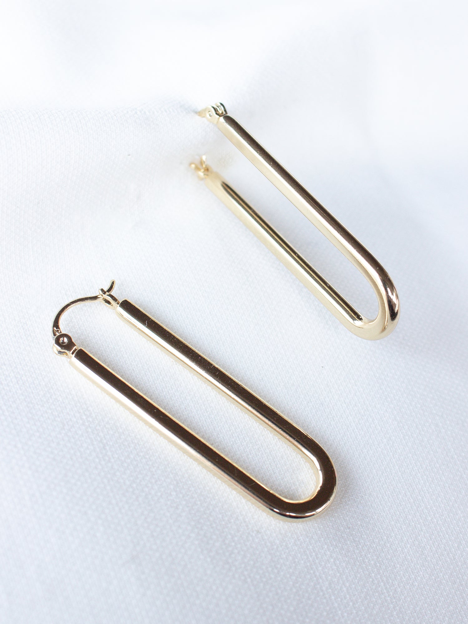 The Kinsey Designs Archives Tate Hoop earrings—a pair of gold filled U-shaped hoops—are shown on a white fabric background. FINAL SALE item.