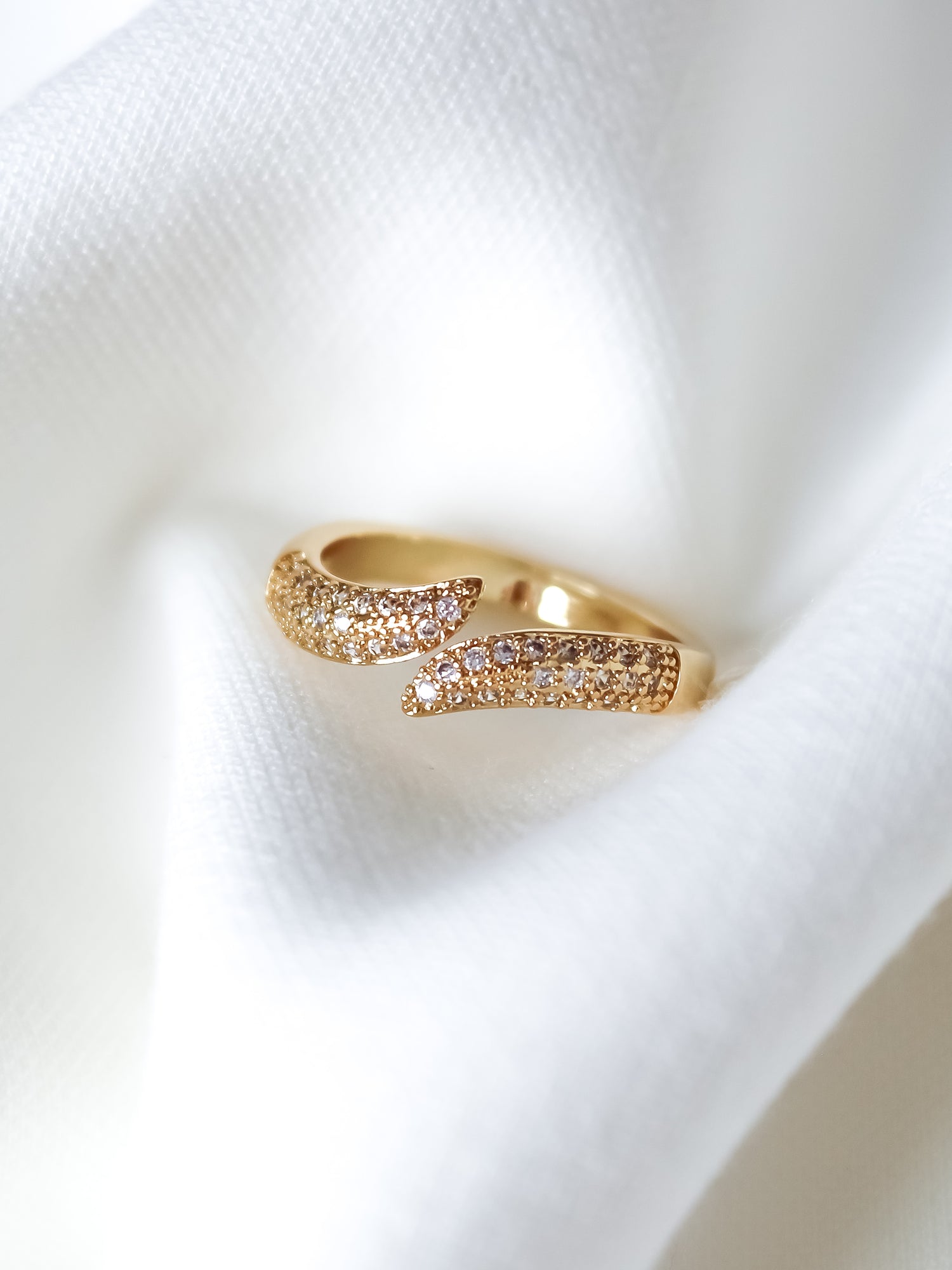 The Venetia Ring by Kinsey Designs, featuring sparkling stones, is elegantly showcased on a soft white fabric background.
