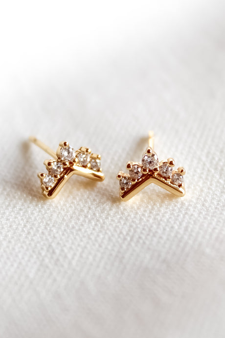 Villa Stud earrings by Kinsey Designs Archives feature small crown shapes with clear sparkling stones, shown on white fabric. Add a touch of elegance—now available in our Sample Sale.