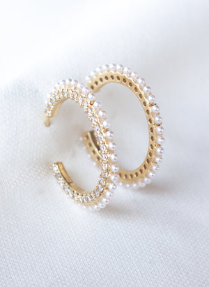 The Whit Hoop by Kinsey Designs Archives features gold-filled hoops adorned with small pearls and sparkling cubic zirconia, displayed on a white fabric background.
