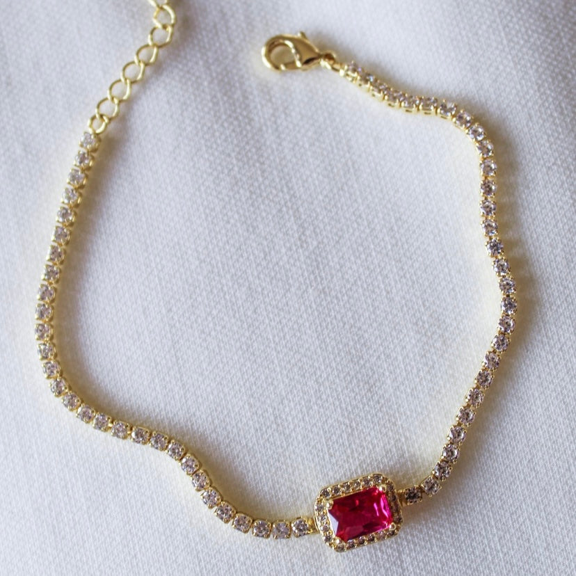 The Lara Bracelet - Fuchsia by Kinsey Designs Archives features gold-filled links, shimmering cubic zirconia accents, and a rectangular fuchsia centerpiece. Displayed on white fabric, it includes an 8" chain for a perfect fit.