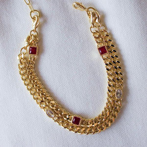 The Kinsey Designs Dublin Bracelet (3 in 1) features gold filled chain links with red and clear cubic zirconia, shown on a white fabric background.