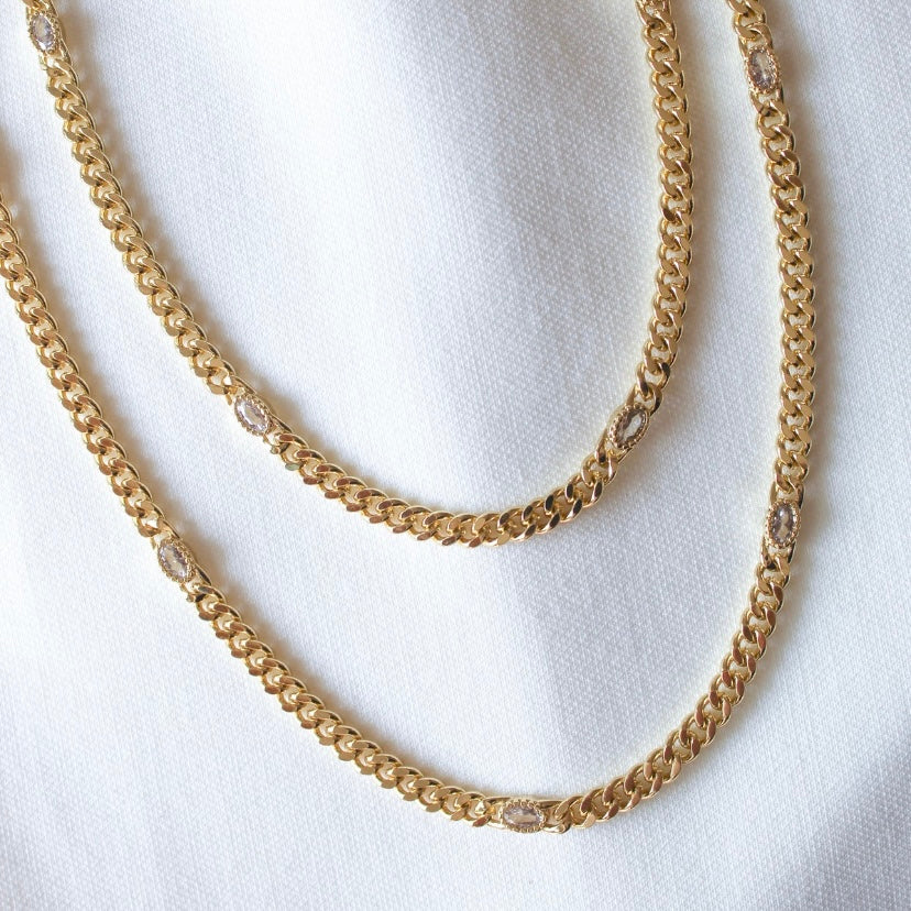 Two Kinsey Designs Lover Necklaces, gold filled with small oval gemstones and sparkling cubic zirconia, displayed on white fabric.