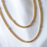 Two Kinsey Designs Lover Necklaces, gold filled with small oval gemstones and sparkling cubic zirconia, displayed on white fabric.