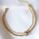 The Flori Bracelet by Kinsey Designs Archives features two unique link styles and an oval cubic zirconia centerpiece, shown on white fabric.