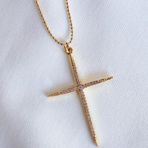 The Meyer Necklace by Kinsey Designs Archives features a gold-filled cross with small diamonds on a delicate 20-inch chain, displayed on white fabric.