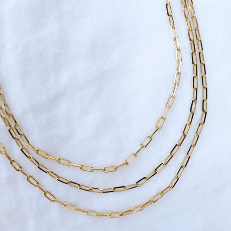 The Carmen Triple Layer by Kinsey Designs Archives showcases three gold filled necklaces with elongated links on a white fabric backdrop, each featuring an extender for adjustable styling as a chic 14-inch necklace.